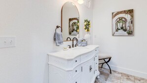 A bathroom with a white vanity, a large mirror, and a framed picture on the wall.
