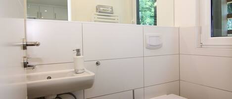 A bathroom with a white sink, toilet, and a window.