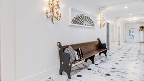 A hallway with a bench, wall sconces, and a decorative fan. - The Mozart's Hideaway Room (Manteo)