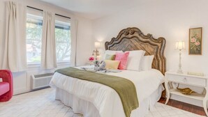 A bedroom with a large bed, a wooden headboard, a bedside table with a lamp, and a window with curtains. - The Ivory Pearl Room/With the best rooftop view in Manteo! (Manteo)