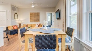 A dining area with a wooden table, blue woven chairs, and a ceiling fan. - The Downtown Delight Family Suite (Manteo)