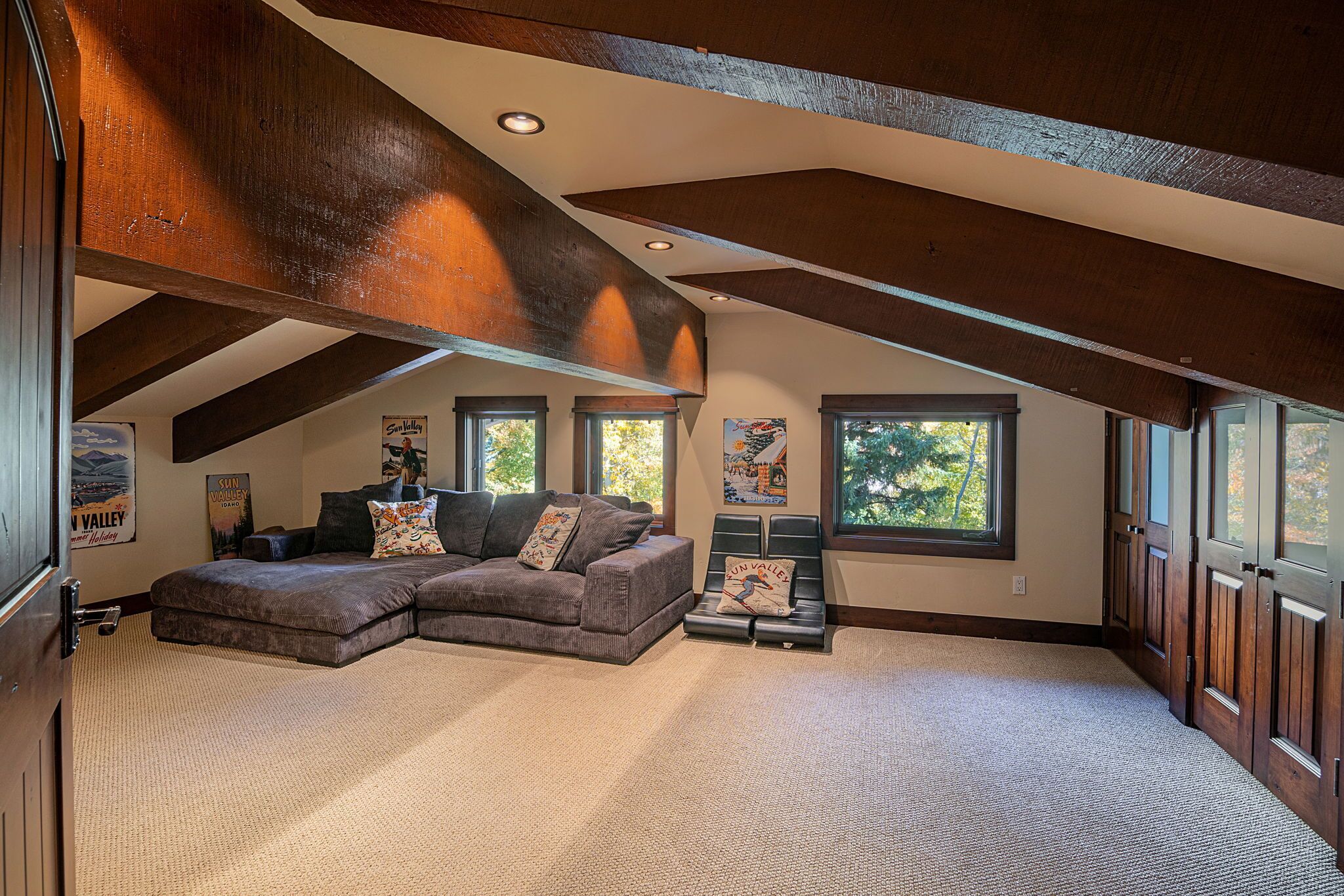 Une chambre spacieuse aménagée en loft, dotée d’une grande fenêtre, d’un canapé d’angle et d’un petit coin salon.