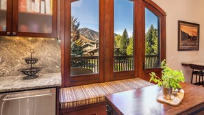 A kitchen with a built-in bench, a wooden cabinet with glass doors, and a view of a mountain landscape. - Beautiful Sun Valley Lodge II Penthouse, sleeps 8 with amazing views of Baldy (Sun Valley)
