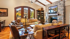A cozy living room with leather sofas, a fireplace, and a stone wall-mounted TV. - Beautiful Sun Valley Lodge II Penthouse, sleeps 8 with amazing views of Baldy (Sun Valley)