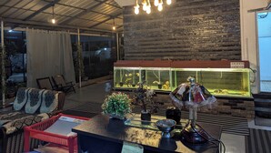 A modern interior with a large aquarium, comfortable seating, and a high ceiling with exposed beams. - NatureVilla Kochi (Aluva)