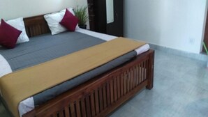 A bed with a wooden frame, grey and beige bedding, and red and white pillows. - NatureVilla Kochi (Aluva)