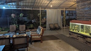 An outdoor seating area with tables and chairs, a fish tank, and potted plants. - NatureVilla Kochi (Aluva)