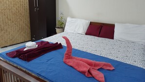 A neatly made bed with a patterned bedspread, a blue mat, and a red towel. - NatureVilla Kochi (Aluva)
