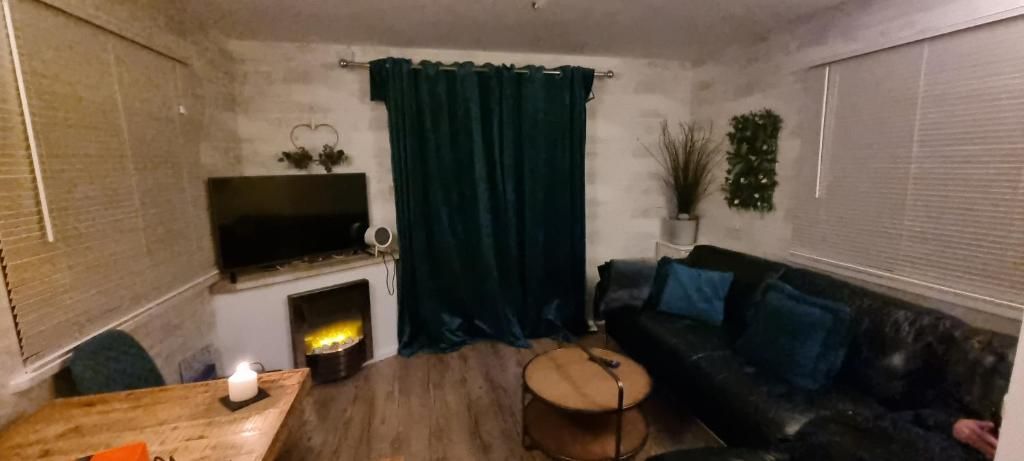 A living room with a fireplace, a sofa, a coffee table, and a television mounted on the wall.