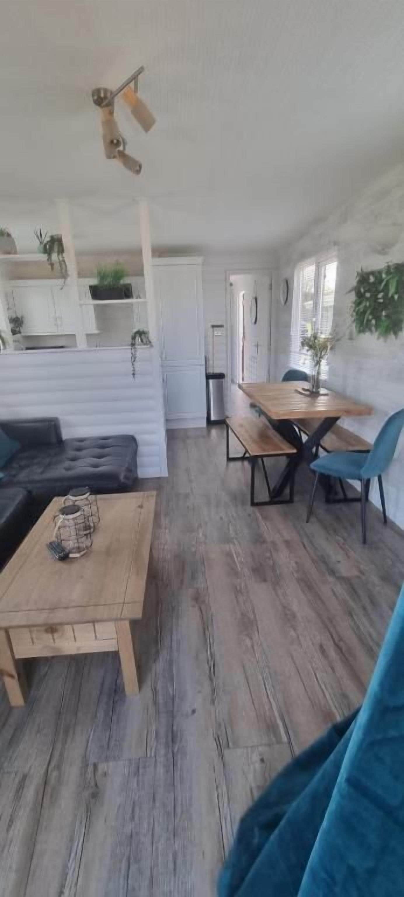 A room with a sofa, a wooden table, and a dining area with chairs.