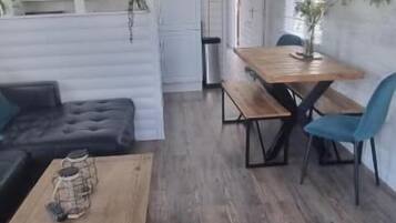 A room with a sofa, a wooden table, and a dining area with chairs.
