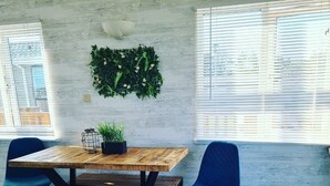 A dining area with a wooden table and chairs, a potted plant, and a wall-mounted green plant. - Haven Holiday Park 42 Pine Lodge (Pwllheli)