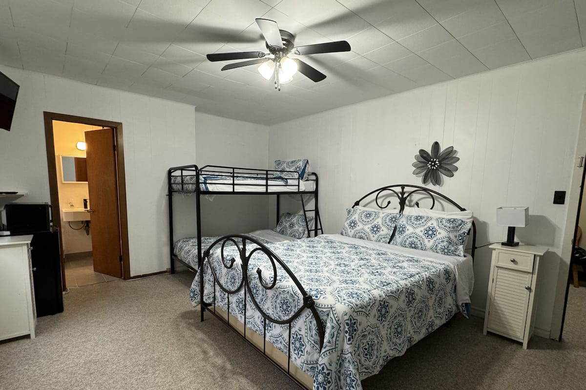A bedroom with bunk beds, a ceiling fan, a nightstand, and a decorative flower on the wall.