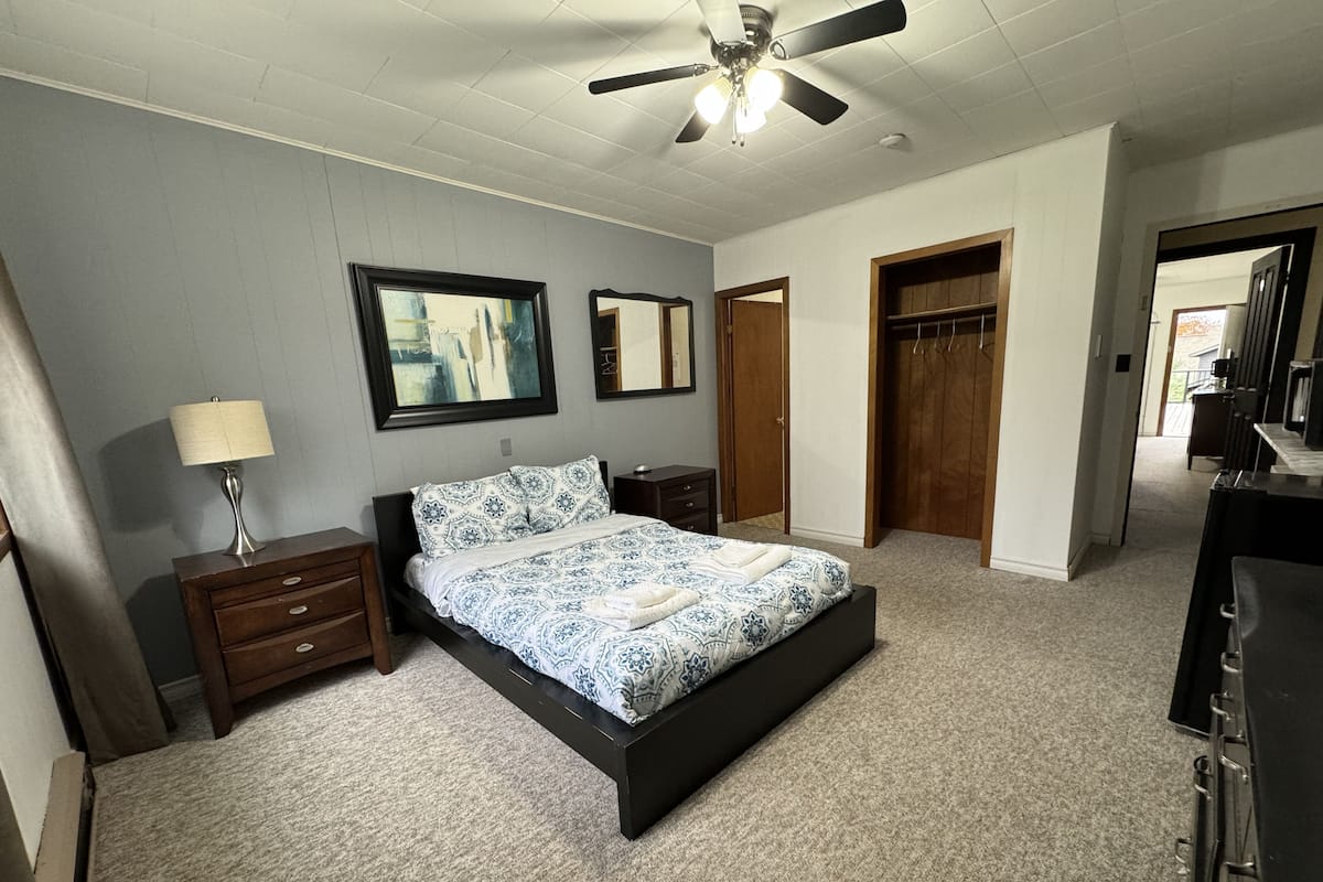 A bedroom with a bed, nightstands, a ceiling fan, and a wardrobe.