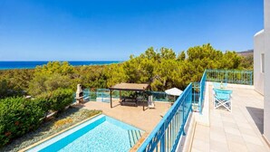 A rooftop terrace with a pool, outdoor seating, and a view of the sea.