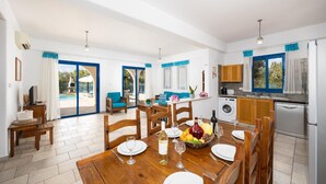 A spacious kitchen with a dining area, a washing machine, and a view of a swimming pool.