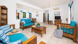 A spacious living room with a sofa, coffee table, and TV stand. There is a staircase leading to another level.