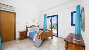 A bedroom with a wooden bed, bedside tables, a desk, and a view through a glass door.