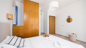 A bedroom with a bed, a wardrobe, a bedside table, a lamp, and a mirror.