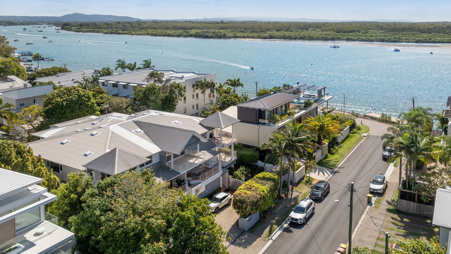 A coastal residential area with modern houses, a road, and a marina with boats.