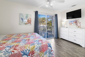 Ein Schlafzimmer mit Bett, Fernseher, Balkon und Blick sowie Deckenventilator.