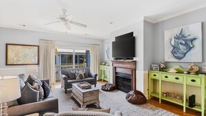 A living room with a sofa, armchair, fireplace, television, and artwork. - Large House w Pool Table, close Restaurants + Beach Access less than 1000 FT (Tybee Island)