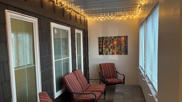 A cozy patio area with a seating arrangement, a table, and string lights.