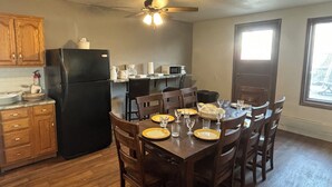 A compact kitchen with a refrigerator, microwave, and dining table set for six.