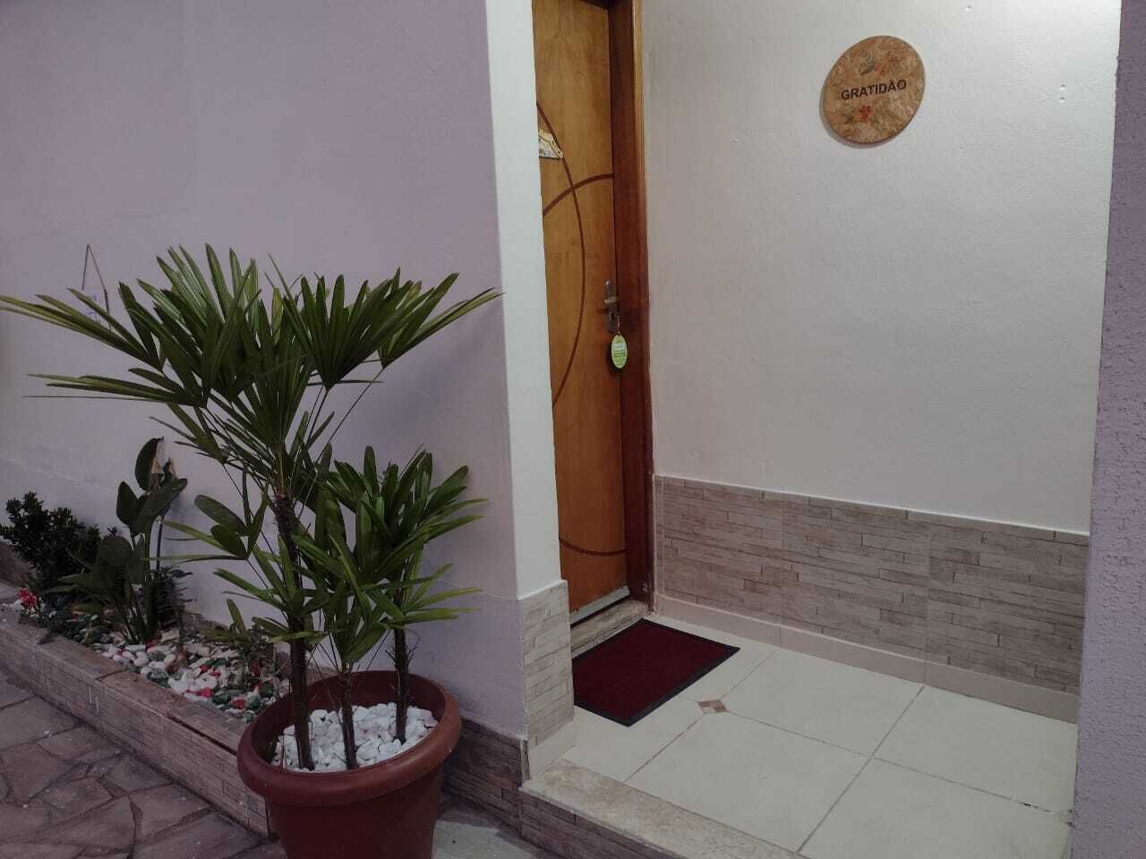 Una planta en maceta, una puerta de madera, un felpudo y una placa en la pared.