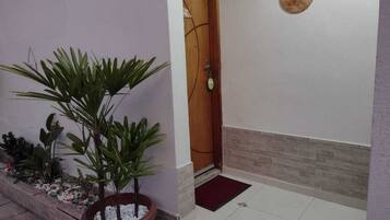 Una planta en maceta, una puerta de madera, un felpudo y una placa en la pared.