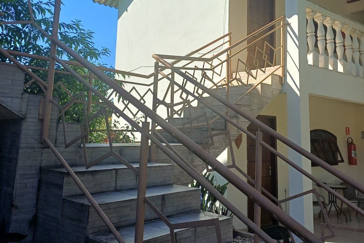 A staircase leading to a building with a balcony, surrounded by greenery.