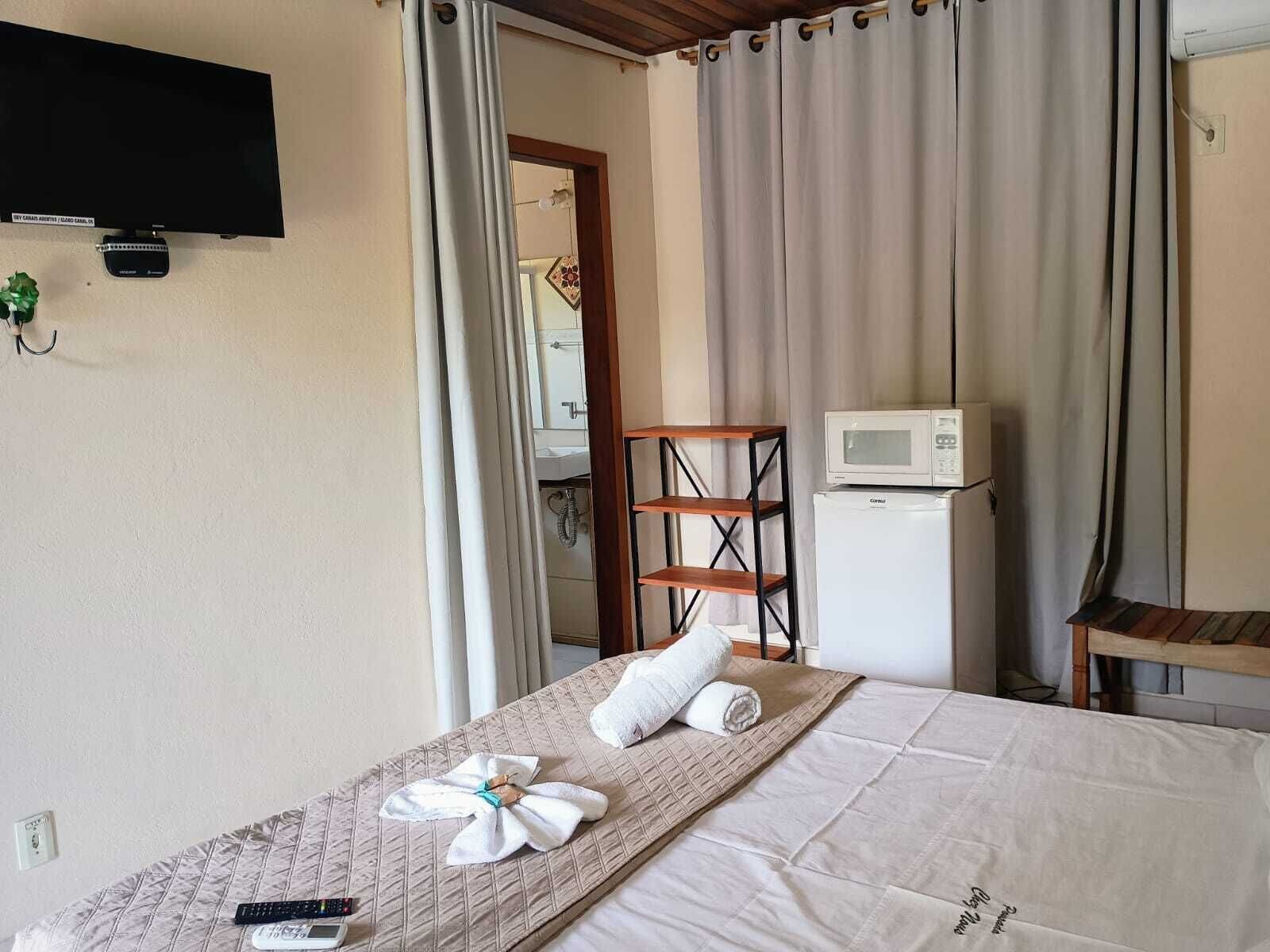 Een hotelkamer met een bed, een televisie, een magnetron en een kleine koelkast.