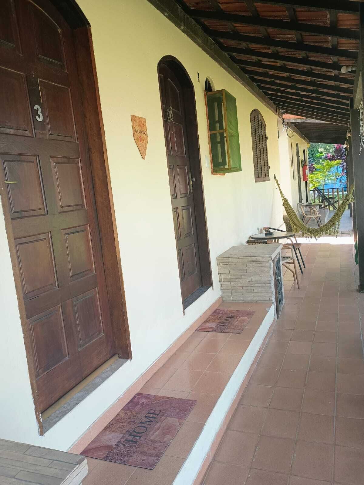 Un porche abrité avec une porte en bois portant le numéro « 3 », un banc en pierre et un hamac.