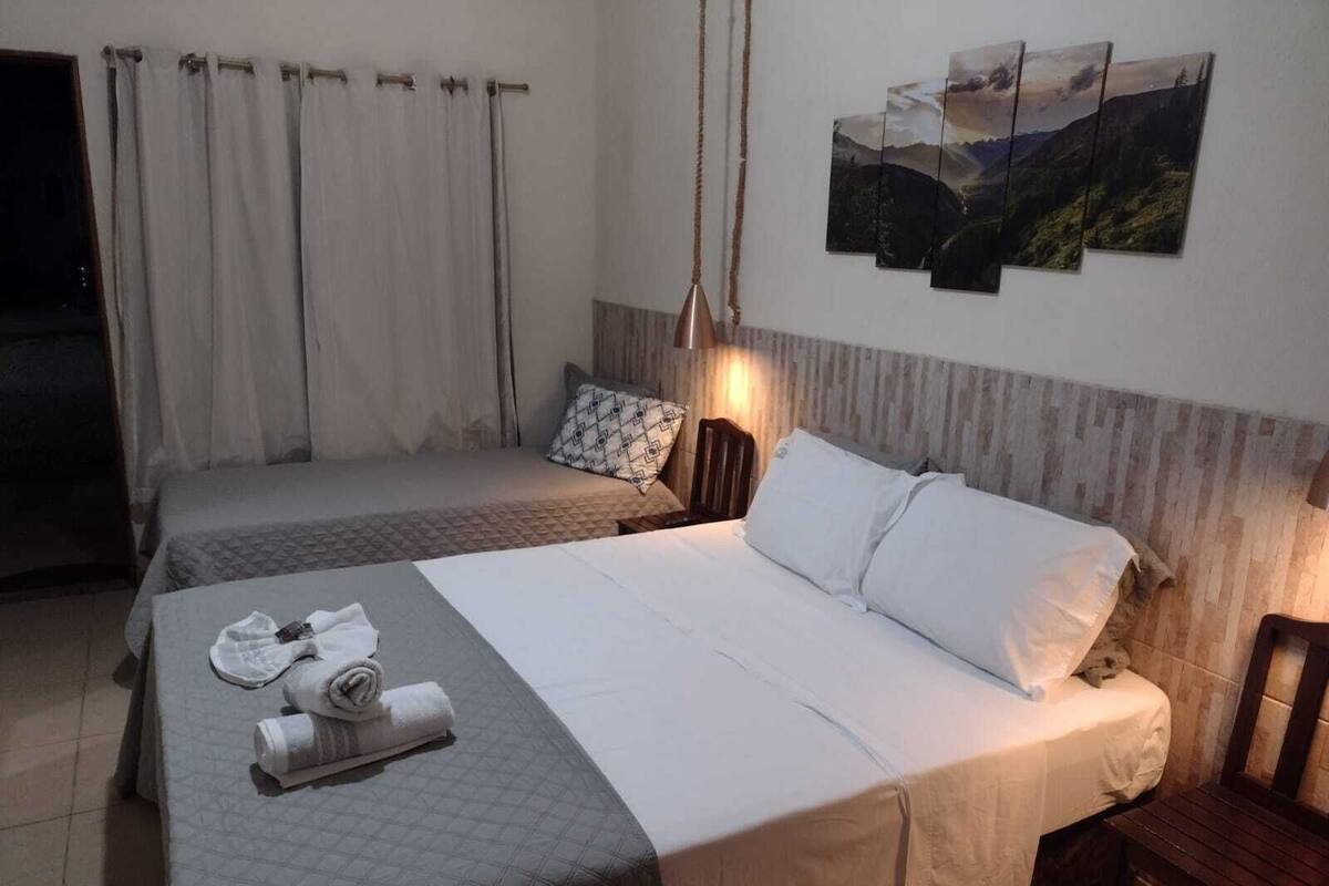A hotel room with two beds, a wooden headboard, a wall-mounted lamp, and a painting.