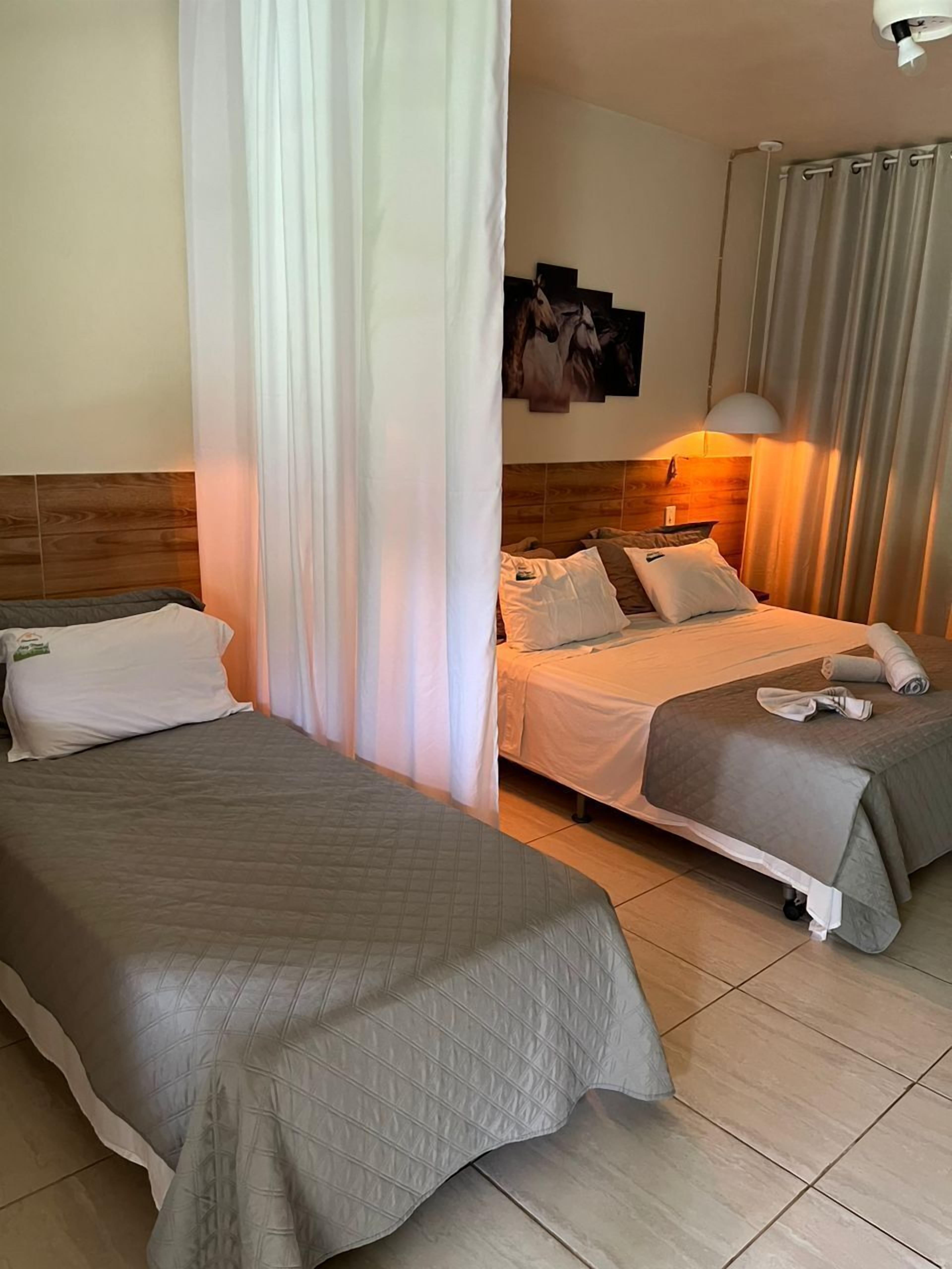 Una habitación de hotel con dos camas, un cabecero de madera, un televisor montado en la pared y una lámpara en el techo.