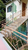 Una escalera con barandillas metálicas de diseño geométrico que conduce a un edificio con un mural.