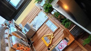 Un buffet avec différents plats présentés dans des récipients transparents, un comptoir en bois avec une enseigne et un panneau indiquant « Il est interdit de fumer ».