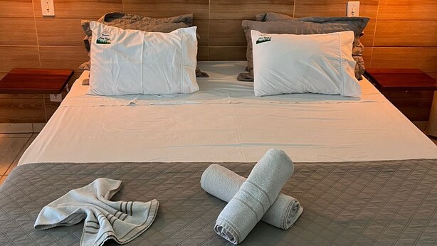 Une chambre d’hôtel avec un grand lit, deux tables de chevet, une tête de lit en bois et une œuvre d’art représentant des chevaux, accrochée au mur.