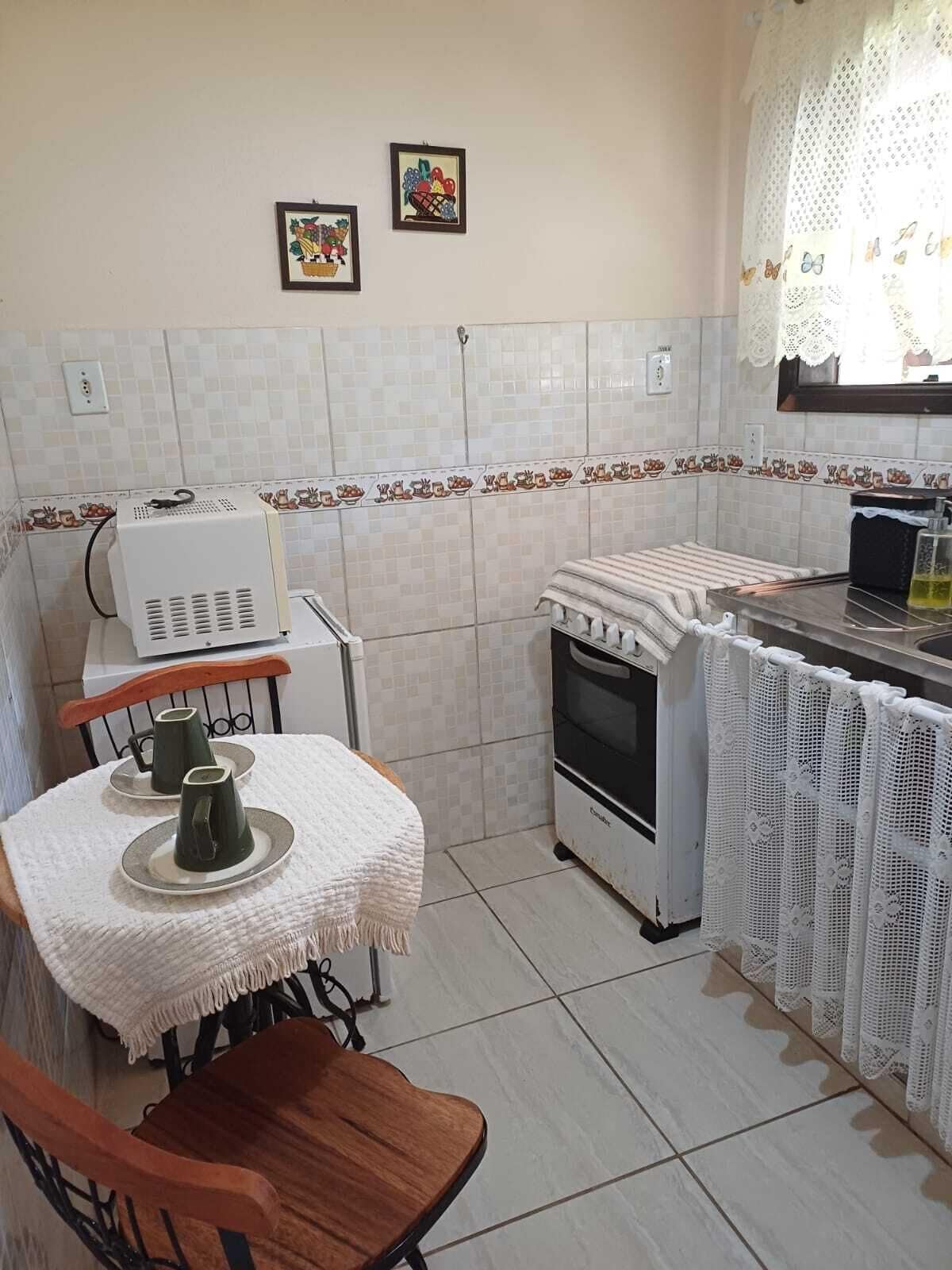 Une cuisine de taille réduite comprenant une table, des chaises, une cuisinière et un réfrigérateur.