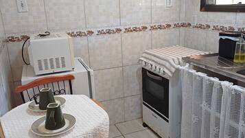 Une cuisine de taille réduite comprenant une table, des chaises, une cuisinière et un réfrigérateur.