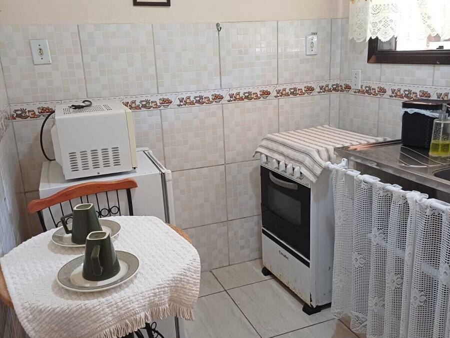 Une cuisine de taille réduite comprenant une table, des chaises, une cuisinière et un réfrigérateur.