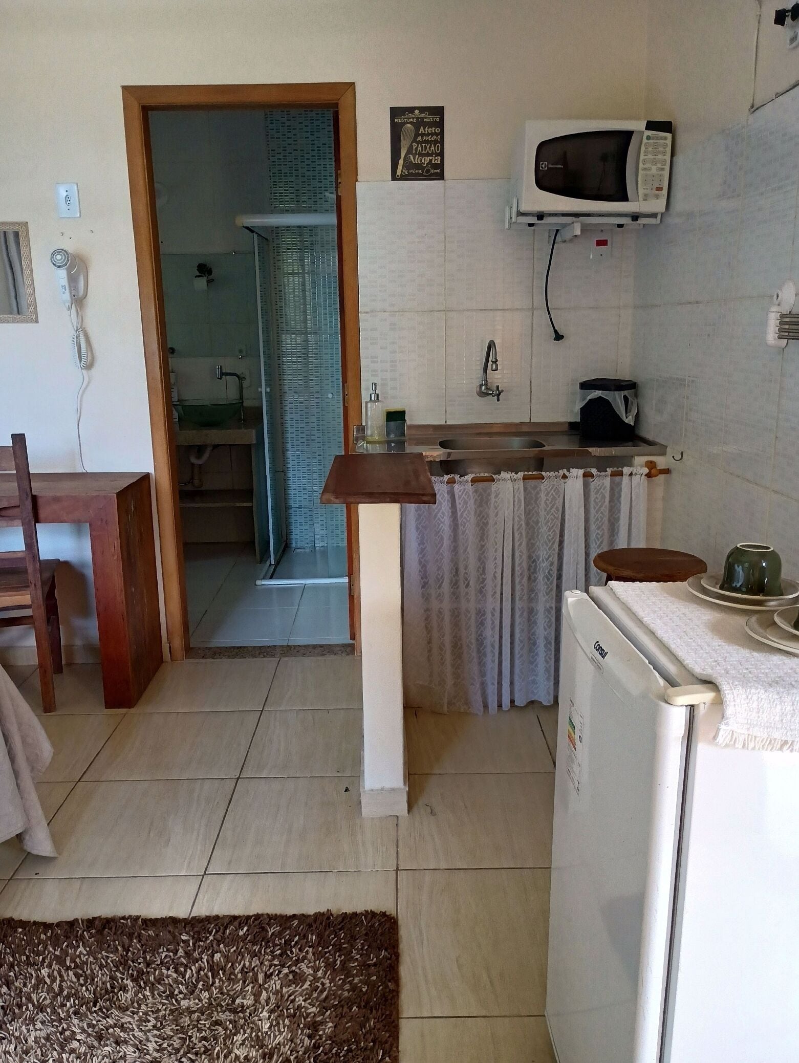 A compact kitchen with a microwave, sink, and a small refrigerator.