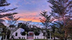 A white building with a central entrance, surrounded by a well-maintained lawn and trees. - Casa Roma - Luxury Villa (El Tamarindo)