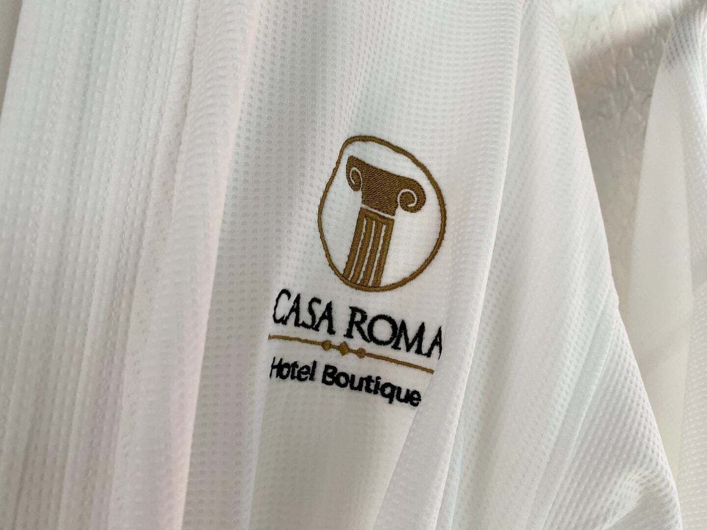 A white fabric with a logo and text reading "CASA ROMA Hotel Boutique".