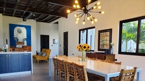 A modern kitchen with a central island, wooden chairs, and a dining table. - Casa Roma - Luxury Villa (El Tamarindo)