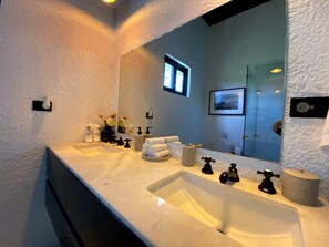 A modern bathroom with a large mirror, two sinks, and a towel rack.