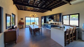 A spacious kitchen with a large island, dark cabinetry, and a view to the outdoors. - Casa Roma - Luxury Villa (El Tamarindo)