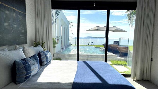 A bedroom with a large bed, a view of a pool, and a balcony with umbrellas. - Casa Roma - Luxury Villa (El Tamarindo)