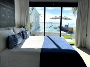 A bedroom with a large bed, a view of a pool, and a balcony with umbrellas. - Casa Roma - Luxury Villa (El Tamarindo)