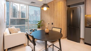 A modern kitchen with a dining area, large windows, and a city view.